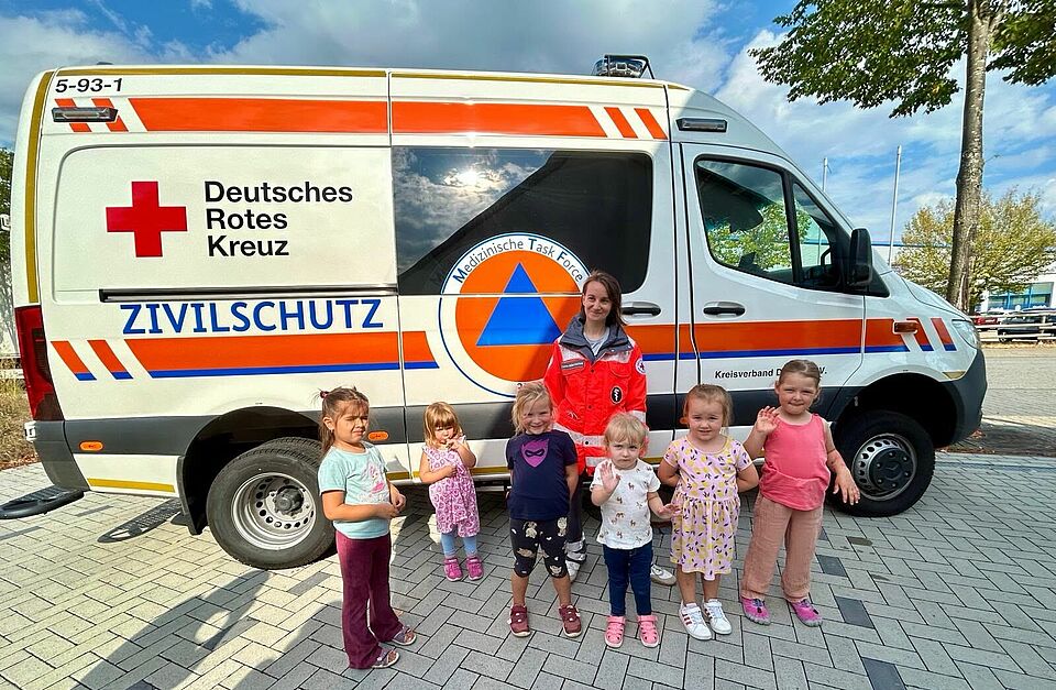 kleine Kinder vor einem Zivilschutz-Krankentransportwagen