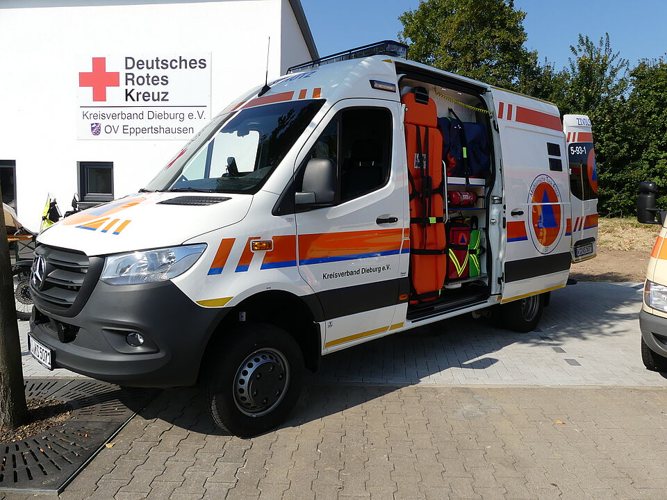 Seitenansicht eines Zivilschutz Krankentransportwagen, in Hintergrund die Fahrzeug- und Gerätehalle des DRK Eppertshausen