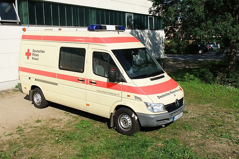 Seitensicht eines 4-Tragen Krankenkraftwagens auf einem Parkplatz vor einer Fahrzeughalle